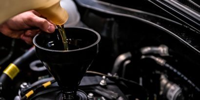 Car mechanic replacing and pouring fresh oil into engine at maintenance repair service station.